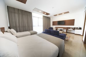 A hotel room with two beds, a sofa, a TV mounted on the wall, and a kitchenette area. - Carissa Hotel (Mugla)