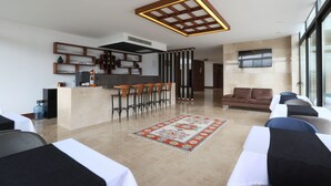 A modern hotel lobby with a reception desk, bar area, seating, and a large TV screen. - Carissa Hotel (Mugla)