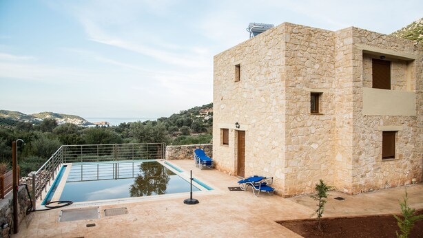 A stone building with a pool and lounge chairs. - Uphoria Stone Villas (Mylopotamos)