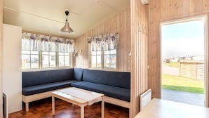 Une pièce avec un canapé bleu, une table en bois et de grandes fenêtres ornées de rideaux à motifs floraux.