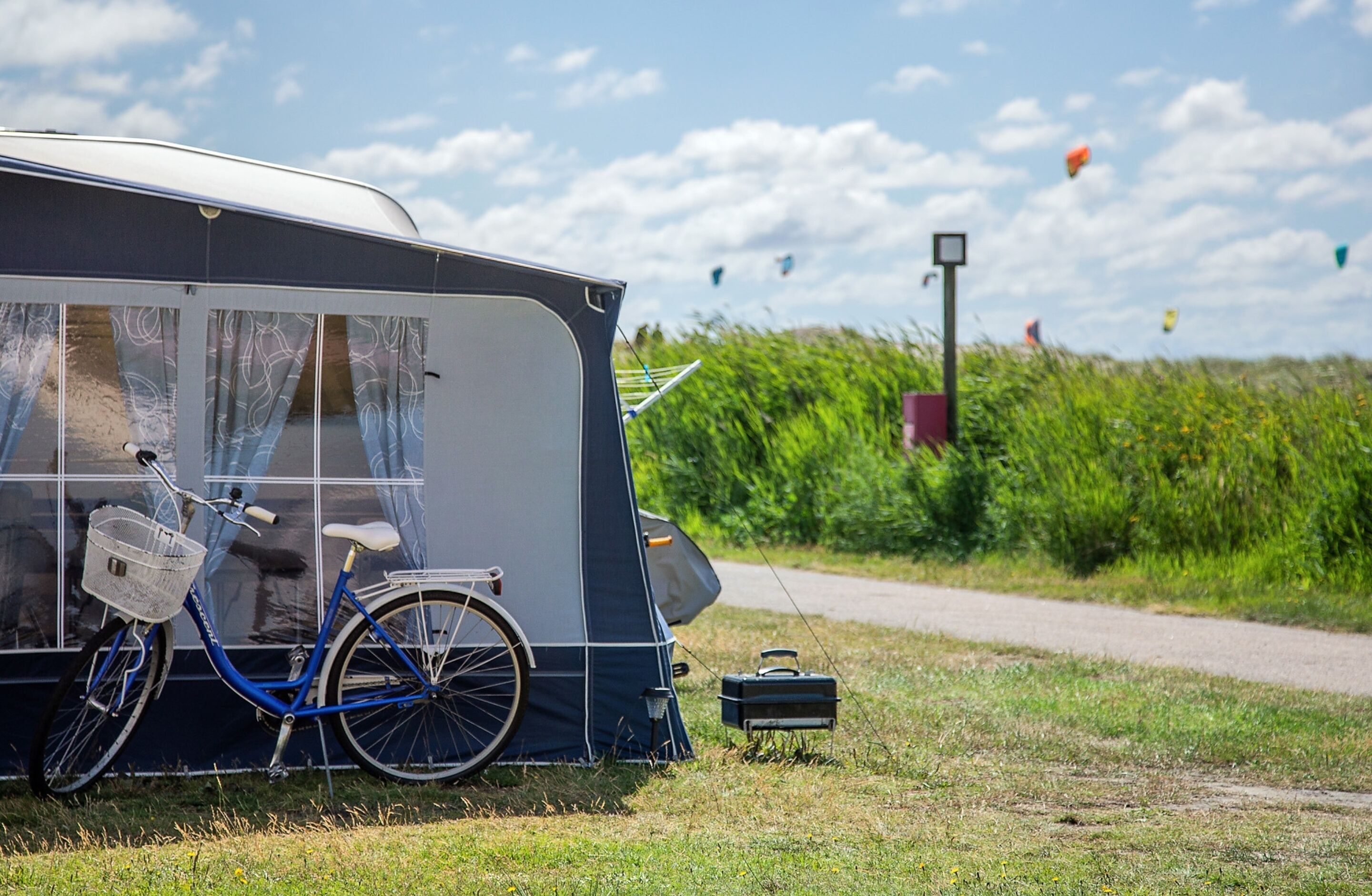 Uma bicicleta azul estacionada ao lado de uma caravana com uma cesta.