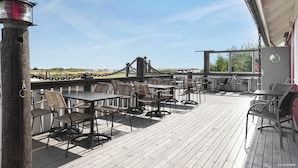 Une terrasse en bois avec des tables et des chaises, une lanterne et une vue sur le paysage.
