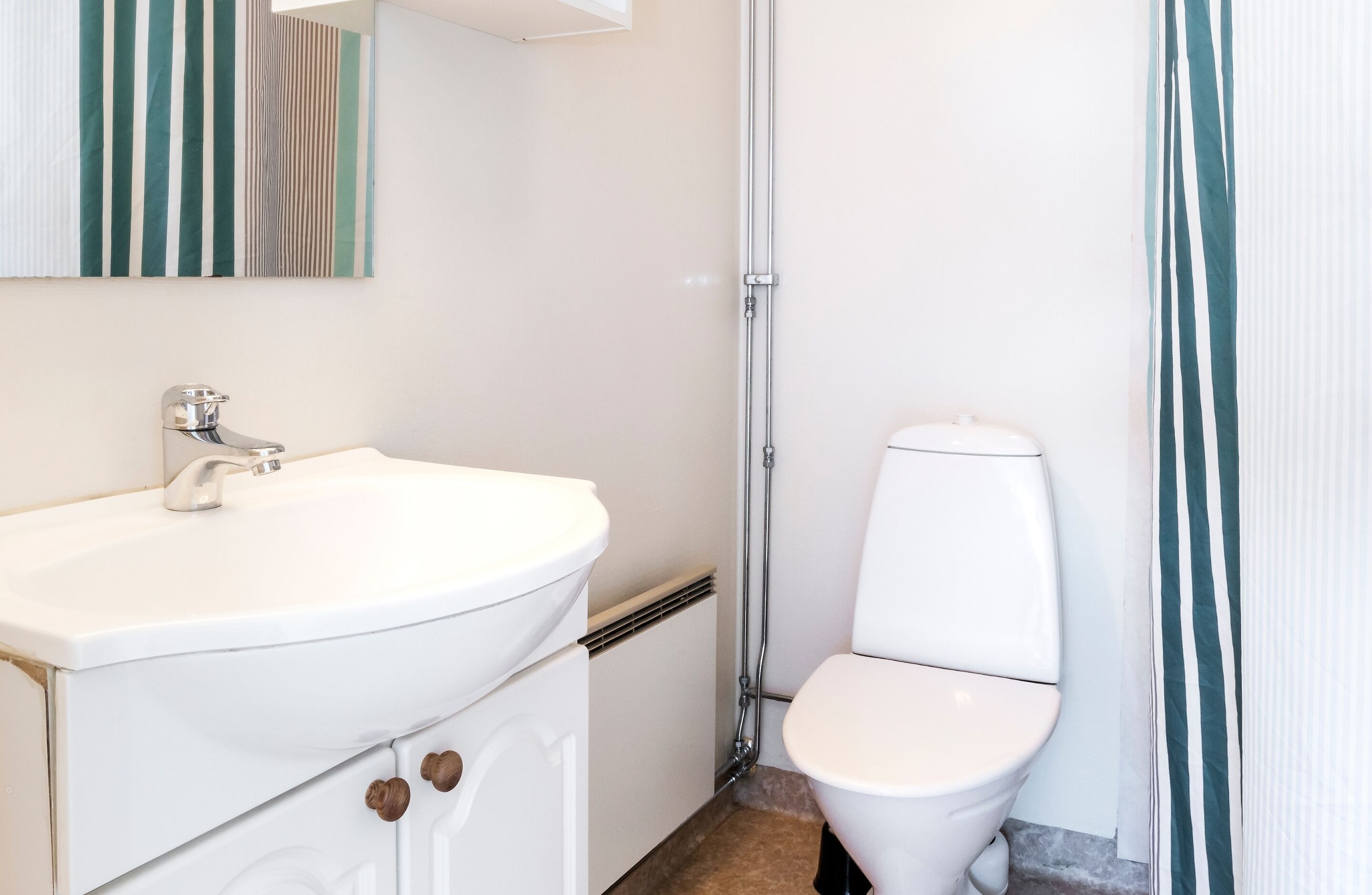 Un baño con lavamanos blanco, inodoro y zona de ducha.
