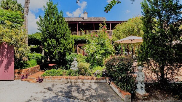 A garden with a statue, a gazebo, and a building with a balcony. - Casa De Solana Bed & Breakfast (St. Augustine)