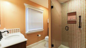 A bathroom with a white sink, a toilet, and a glass-enclosed shower area.