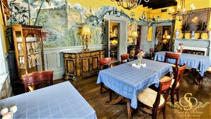 A dining area with blue tablecloths, wooden chairs, and a mural on the wall. - Casa De Solana Bed & Breakfast (St. Augustine)