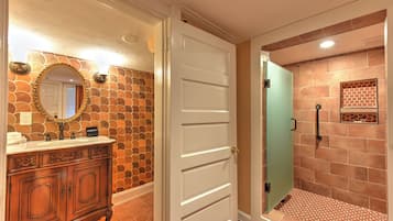 A bathroom with a stone-patterned wall, a white door, and a shower area with a tiled floor.