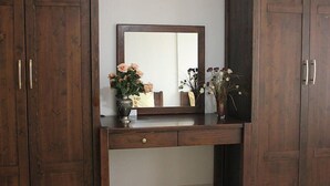 A wooden vanity with a mirror, two vases with flowers, and a small cabinet below. - Kayiboyu Otel (Beypazari)