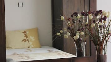 Un dormitorio con una cama, un espejo y dos jarrones con flores.
