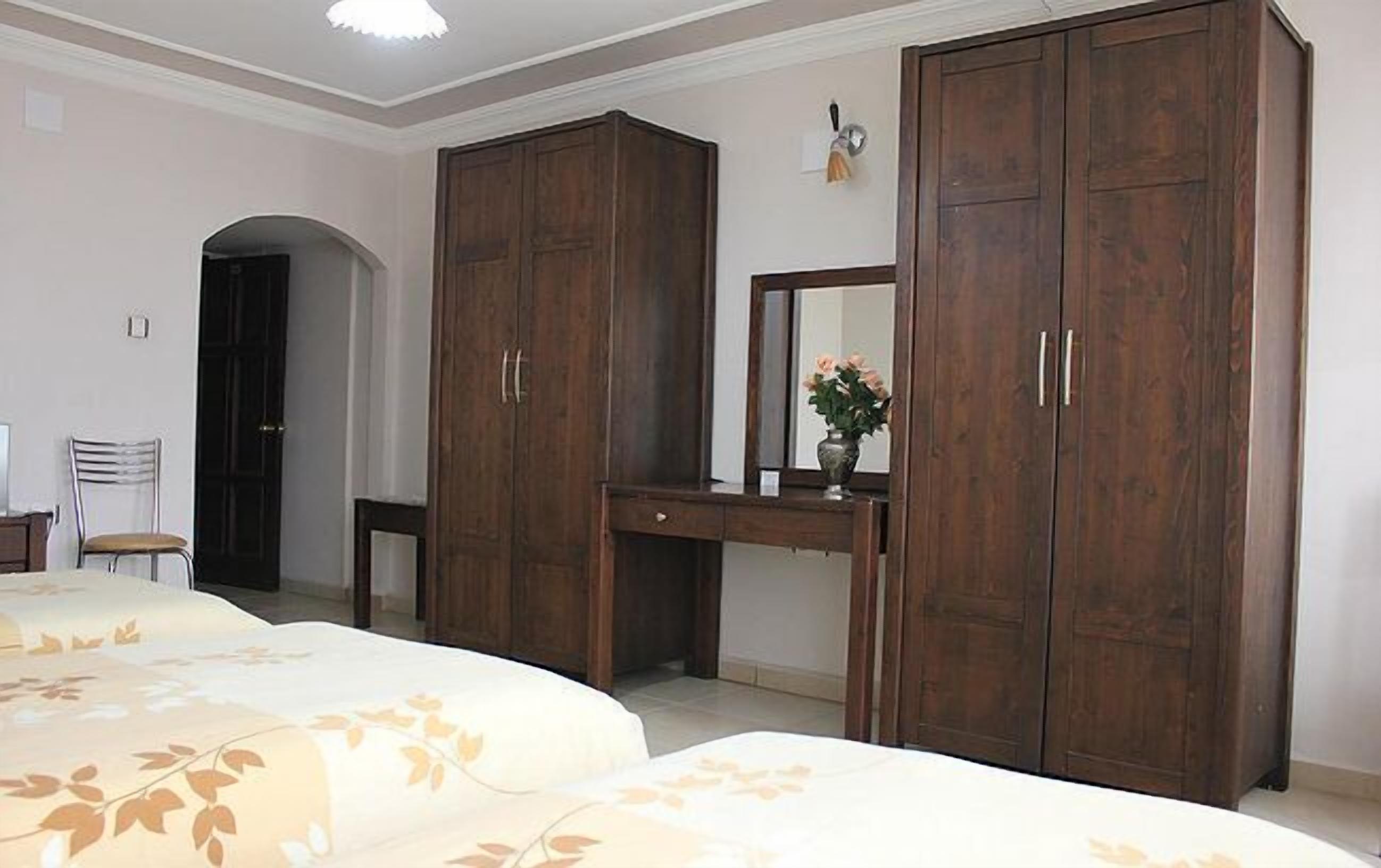 Un dormitorio con dos camas, un aparador y un armario.