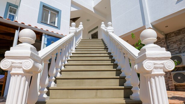 Una escalera con barandillas blancas y peldaños color beige que conduce a la entrada de un edificio.