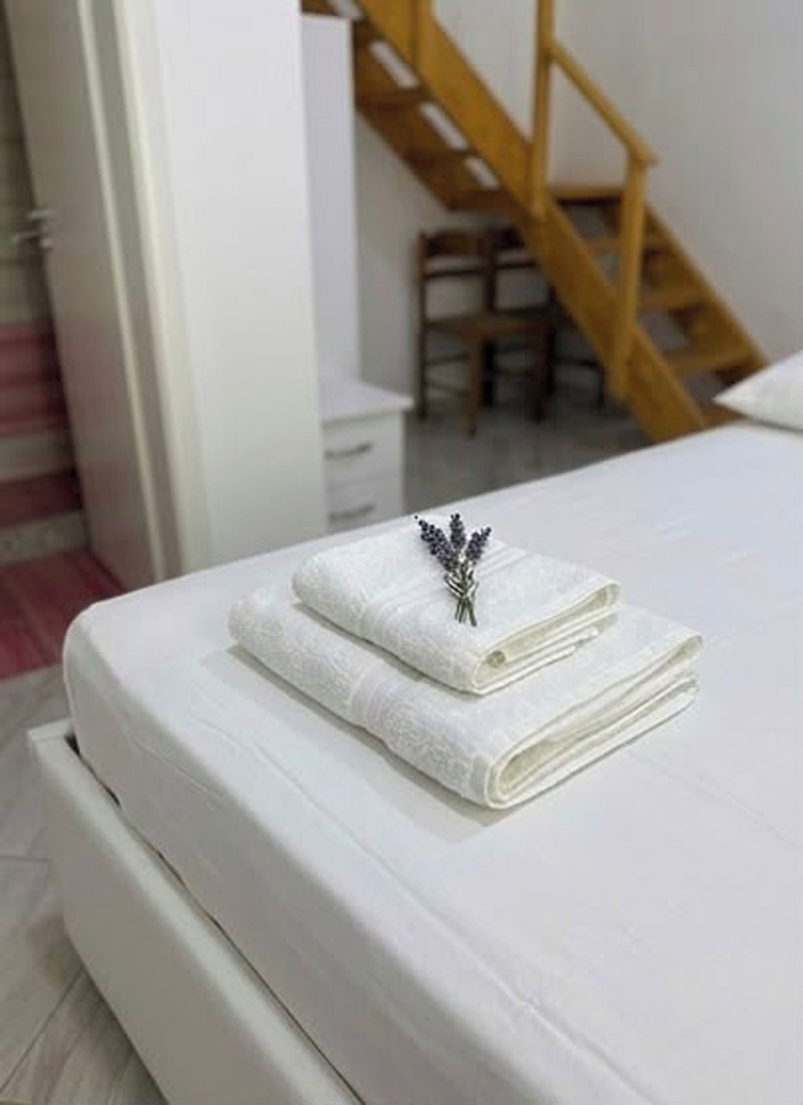 Un lit bien fait, avec une serviette blanche pliée et un objet décoratif posé sur le dessus.