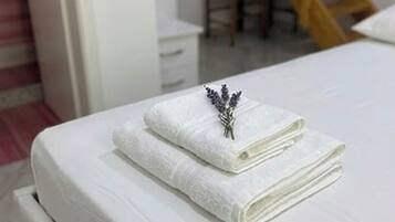 Un lit bien fait, avec une serviette blanche pliée et un objet décoratif posé sur le dessus.