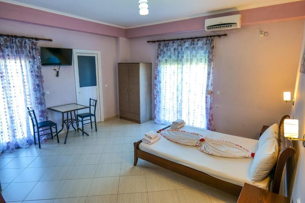 A bedroom with a bed, a desk, chairs, a wardrobe, and a TV.
