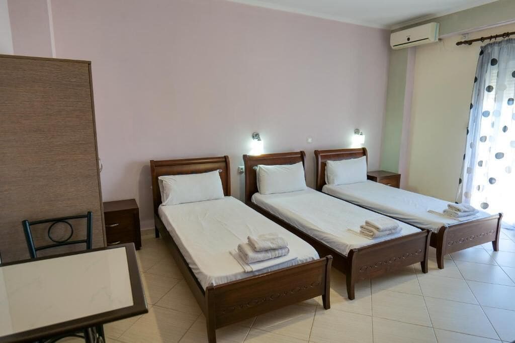 Una habitación de hotel con tres camas individuales, una mesita y una silla.