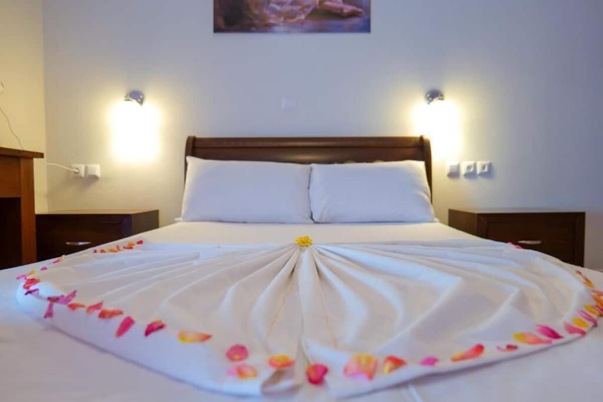 A neatly made bed with a white duvet and a decorative arrangement of flowers.