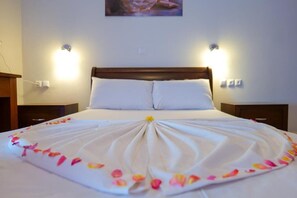 Ein ordentlich bezogenes Bett mit einer weißen Daunendecke und einer dekorativen Blumenanordnung.