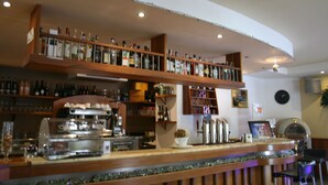 Eine Bar mit Regalen voller Flaschen, einer Kaffeemaschine und einer Jukebox.