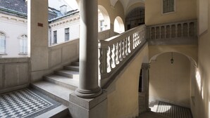 Una gran escalera con barandillas ornamentales, piso a cuadros y arquitectura clásica.