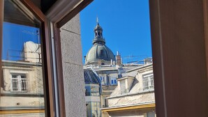 Vista a través de una ventana que muestra un edificio con cúpula y una cruz en la parte superior, lo que sugiere un edificio religioso o histórico.