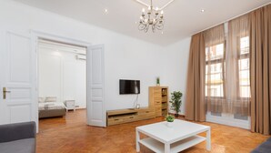 Una sala de estar moderna con un sofá blanco, una mesa de centro blanca, un televisor y un mueble de madera.