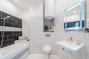 A modern bathroom with a bathtub, toilet, and sink. - Real Apartments Anker koz (Budapest)
