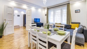 Una sala moderna con comedor, un sofá y una televisión.