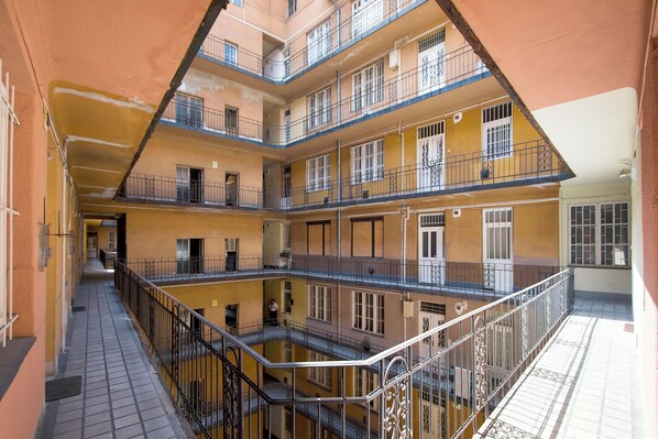 Un edificio residencial de varios niveles con balcones, barandillas y suelo de baldosas.