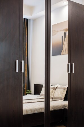 A bedroom with a bed, a nightstand, a wall-mounted artwork, and a dark wooden wardrobe. - Real Apartments Kertesz (Budapest)