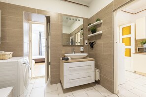 Un baño moderno con un espejo grande, un lavamanos y un calentador integrado.