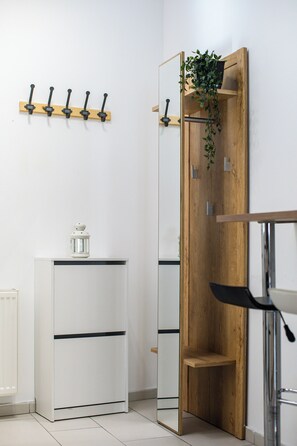 Un baño moderno con un mueble blanco, un armario espejo de madera y una silla negra.