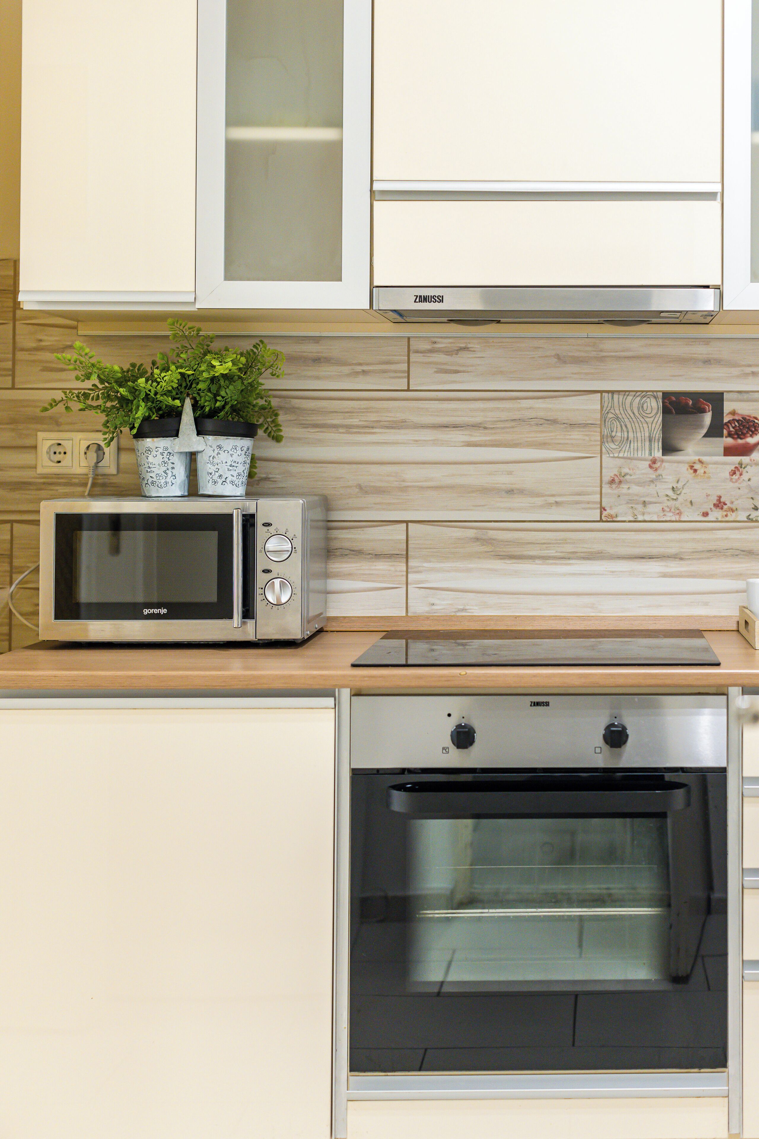 Una cocina con microondas, horno y plantas en macetas sobre la encimera.