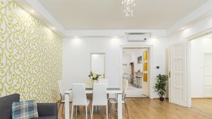 Una sala de estar moderna con sofá, mesa de comedor y sillas, una pared con diseño y una puerta que da a otra habitación.