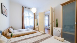 A hotel room with two beds, a washing machine, and a large window with curtains. - Real Apartments Lovag (Budapest)