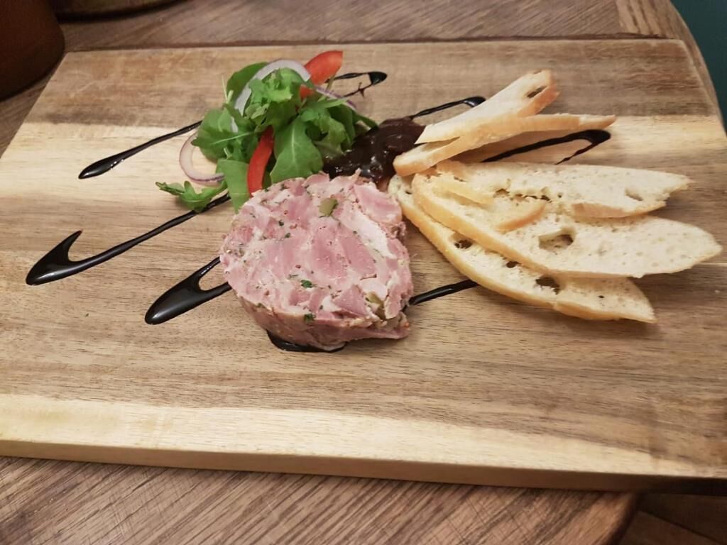 Un tagliere con un piatto di carne, insalata e fette di pane.