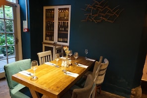 A dining table set with wine glasses and cutlery, a vase with flowers, and a wine rack in the background. - The Barge Inn (Bradford-on-Avon)