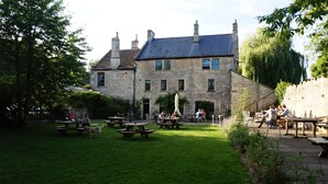 Un edificio de piedra con un patio, mesas de picnic y asientos al aire libre.