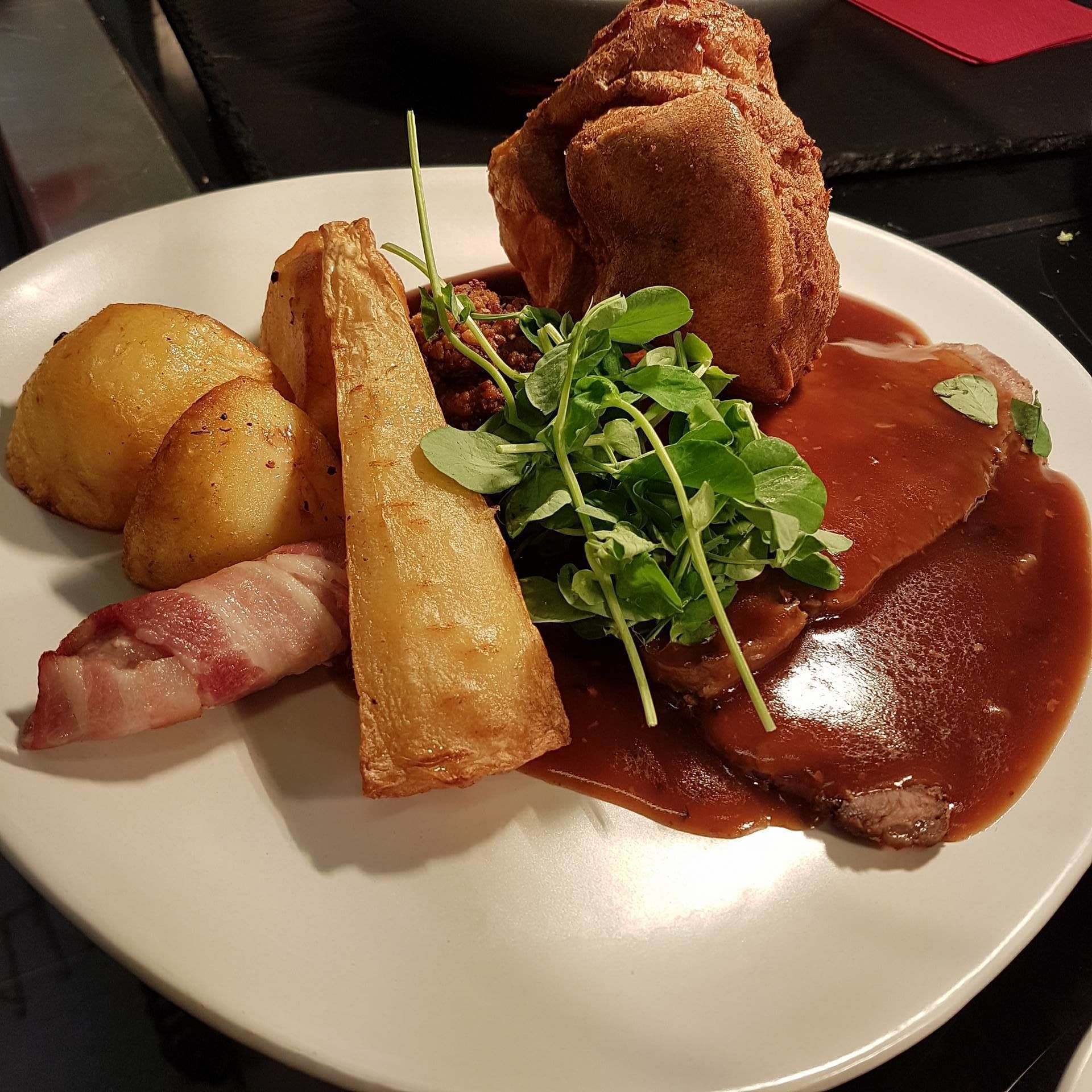 A plate with roasted meat, potatoes, and greens.