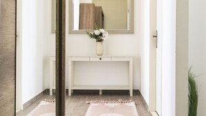 A hallway with a white console table, a mirror, and a vase with flowers. - Real Apartments Revay (Budapest)