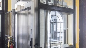 An elevator with a glass enclosure and metal railings. - Real Apartments Revay (Budapest)