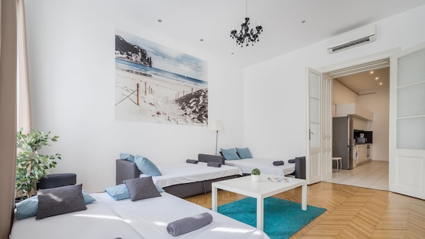 A modern hotel room with two beds, a small table, and a view of a beach. - Real Apartments Vadasz (Budapest)