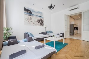 A modern hotel room with two beds, a small table, and a view of a beach. - Real Apartments Vadasz (Budapest)
