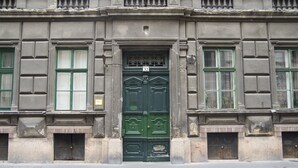A building facade with a green door, numbered 32, flanked by windows with green frames. - Real Apartments Vadasz (Budapest)
