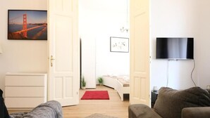 Un salon avec un canapé, un tapis rouge et un téléviseur fixé au mur.