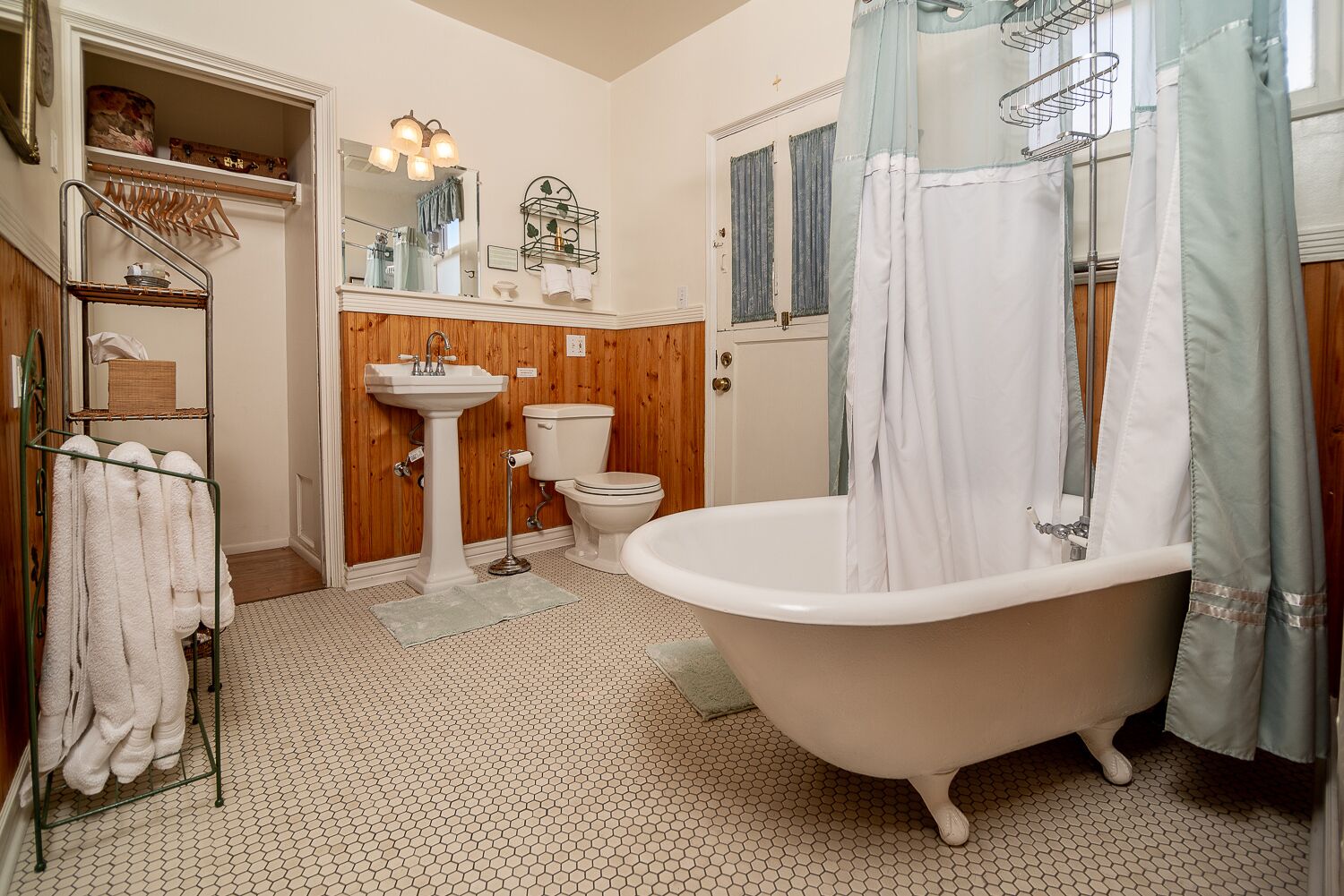 A bathroom with a clawfoot bathtub, a pedestal sink, and a toilet.