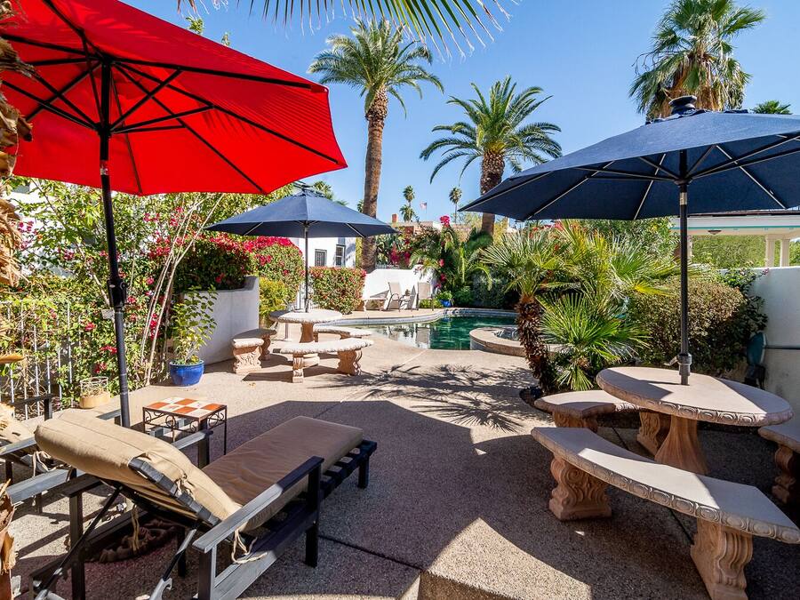 A patio area with outdoor furniture, two umbrellas, and a pool.