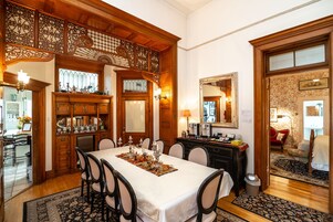 A dining area with a wooden buffet, a large mirror, and a floral wallpapered wall.