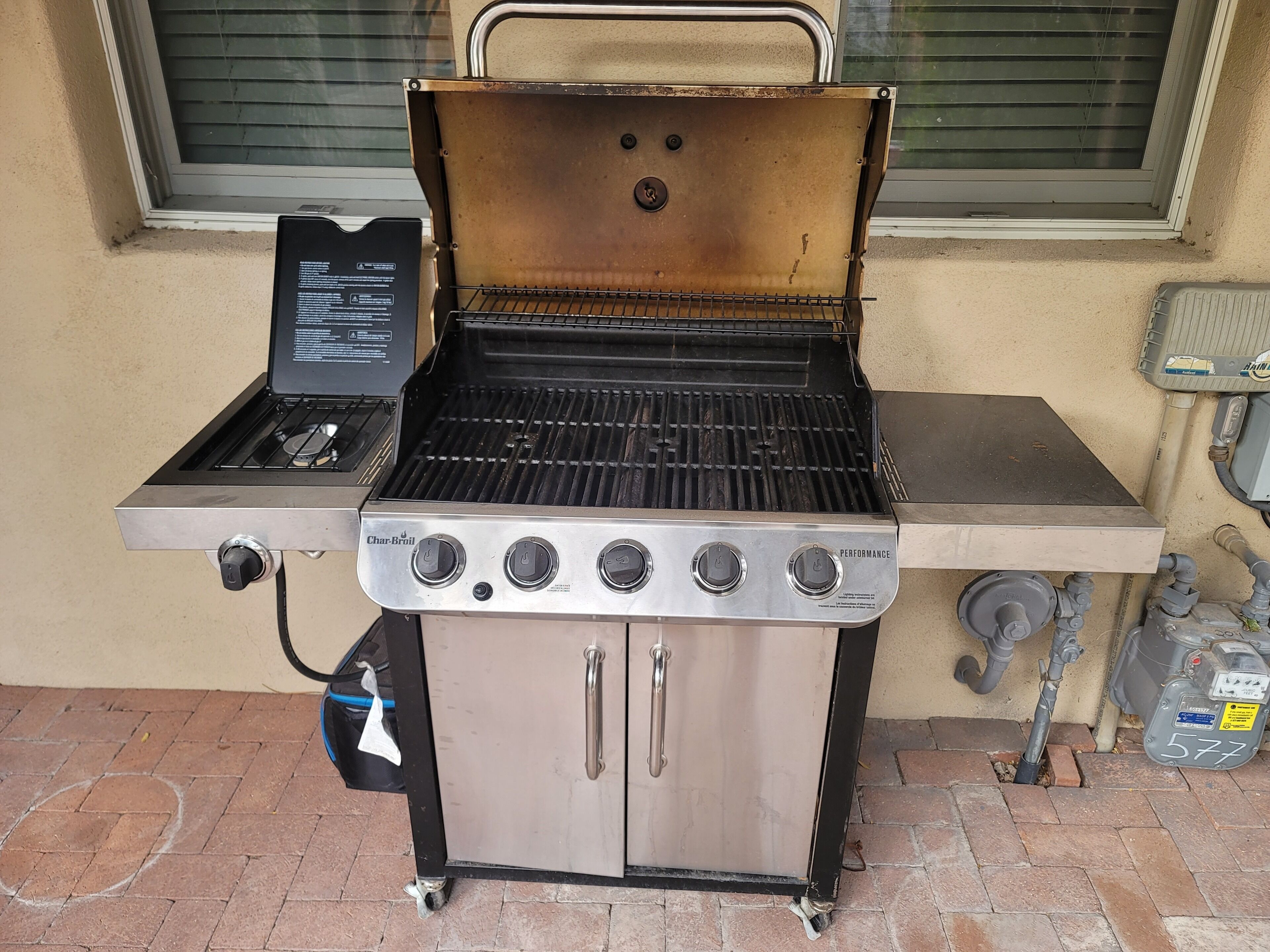 A Char-Broil gas grill with four burners, a side burner, and a storage cabinet.