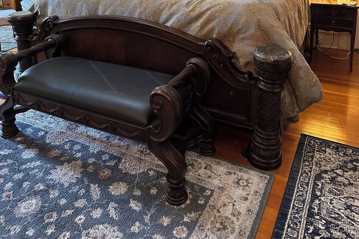 Une chambre à coucher classique, avec un grand lit, une tête de lit décorée et deux lampes de chevet.