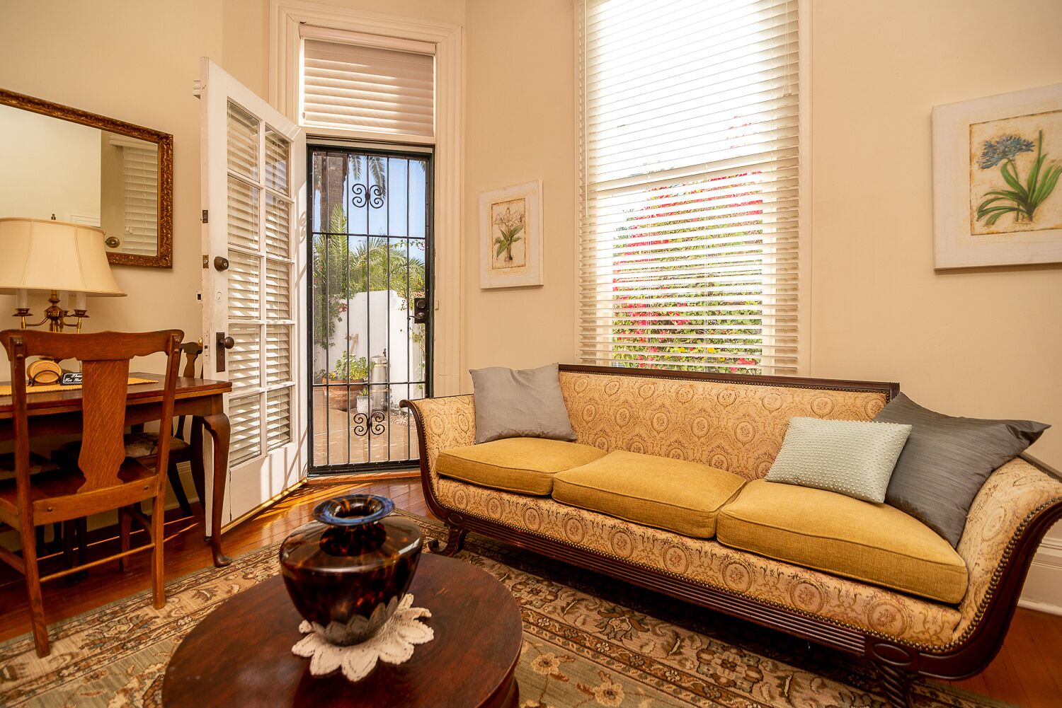 A living room with a sofa, a coffee table, a chair, a lamp, and a door leading to a balcony.